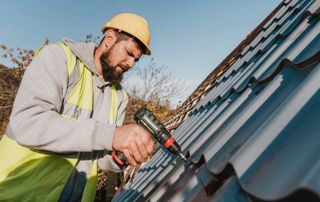 couvreur réparant les tuiles d'une toiture