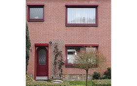 façade en brique avec porte et châssis rouges