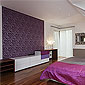 Chambre à coucher avec papier peint mauve et parquet en bois foncé