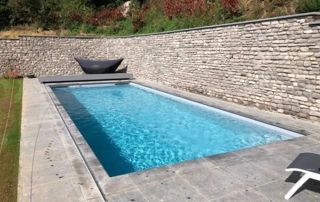 grande piscine extérieure cachée par un muret en briques