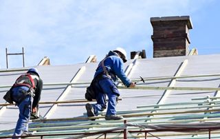 couvreurs en train de travailler sur un toit en pente