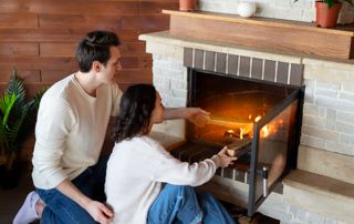 Un couple remet du bois dans le feu ouvert