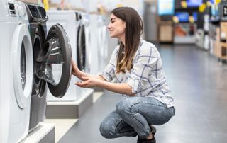 Femme regardant une machine à laver dans un magasin