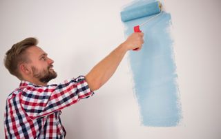 Peintre avec un rouleau de peinture bleue